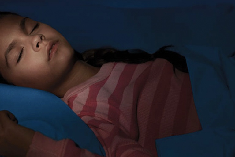 A child in a striped red shirt sleeping soundly in her bed