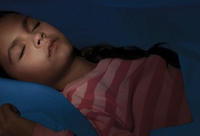 A child in a striped red shirt sleeping soundly in her bed