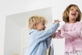 Niño y niña riendo y jugando dentro